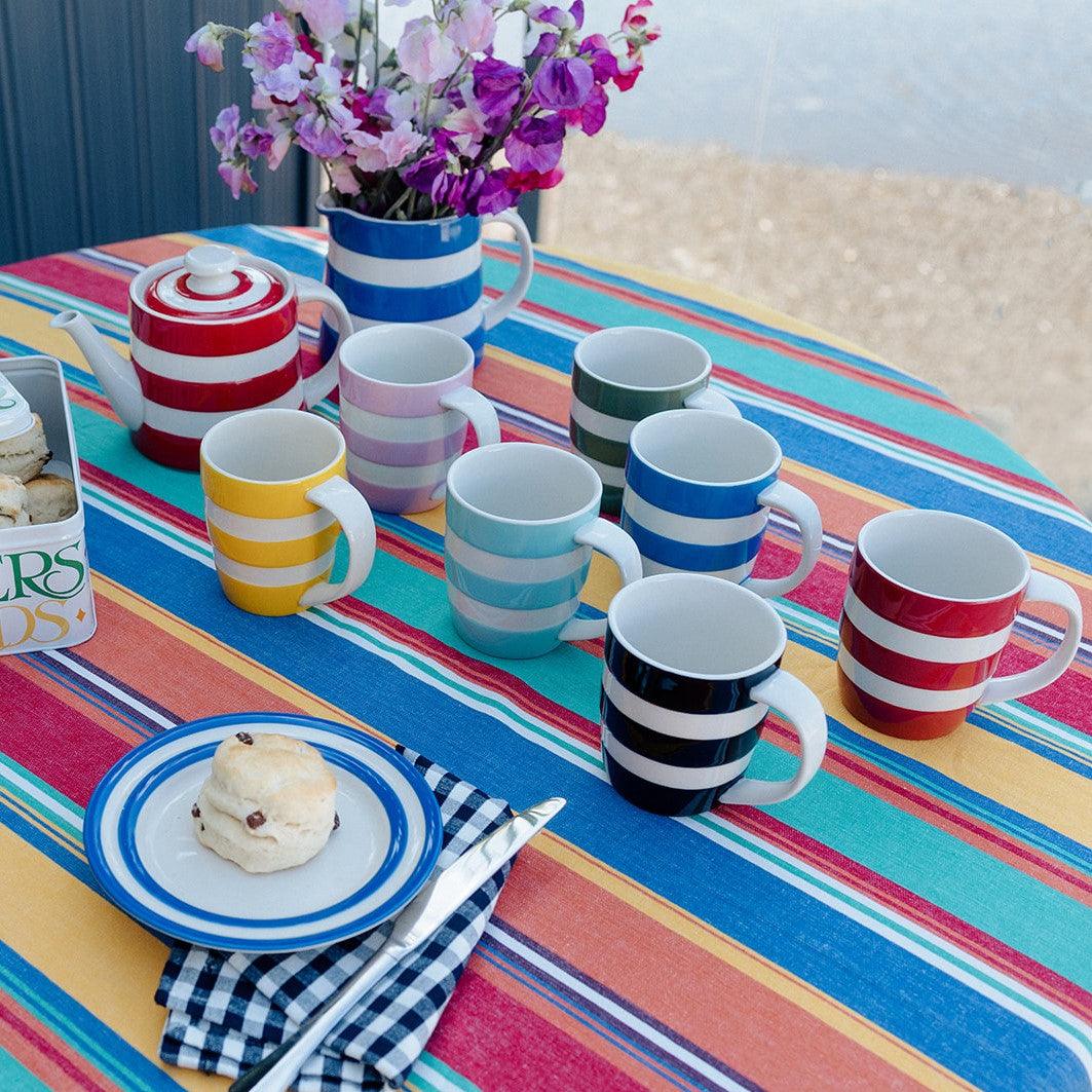 Cornishware coloured mugs displayed on stripey tablecloth- Rubys Home Store 
