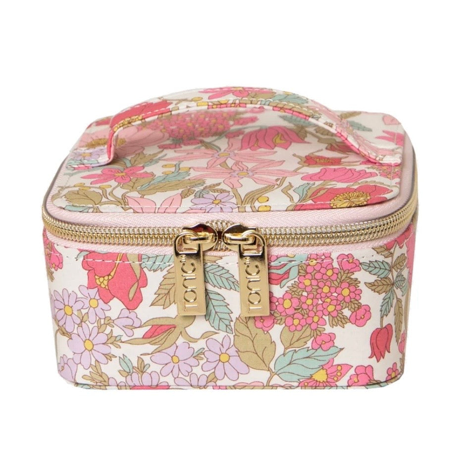 A square cosmetic case with a floral print in pink, green, and beige on a white background, featuring gold-tone zippers and dual pull tabs.