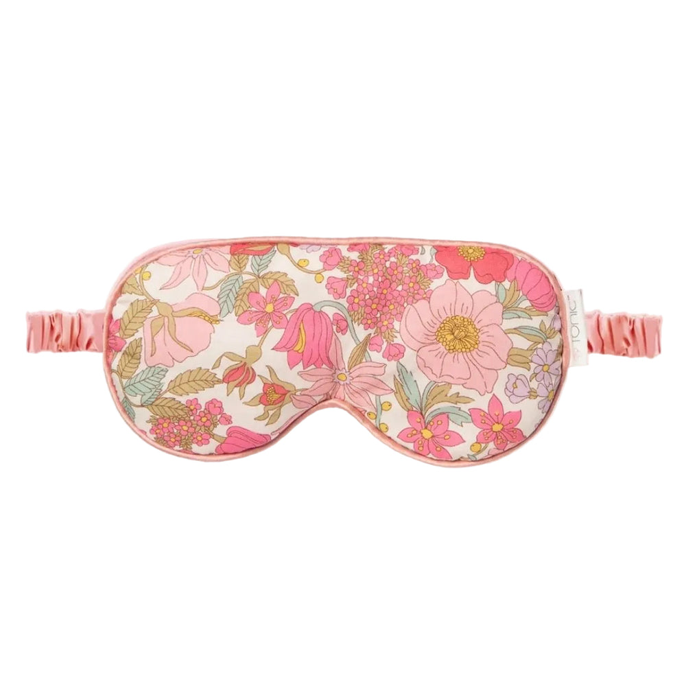 A floral sleep mask with a pink and cream pattern, featuring a matching pink elastic strap, shown against a plain white background.