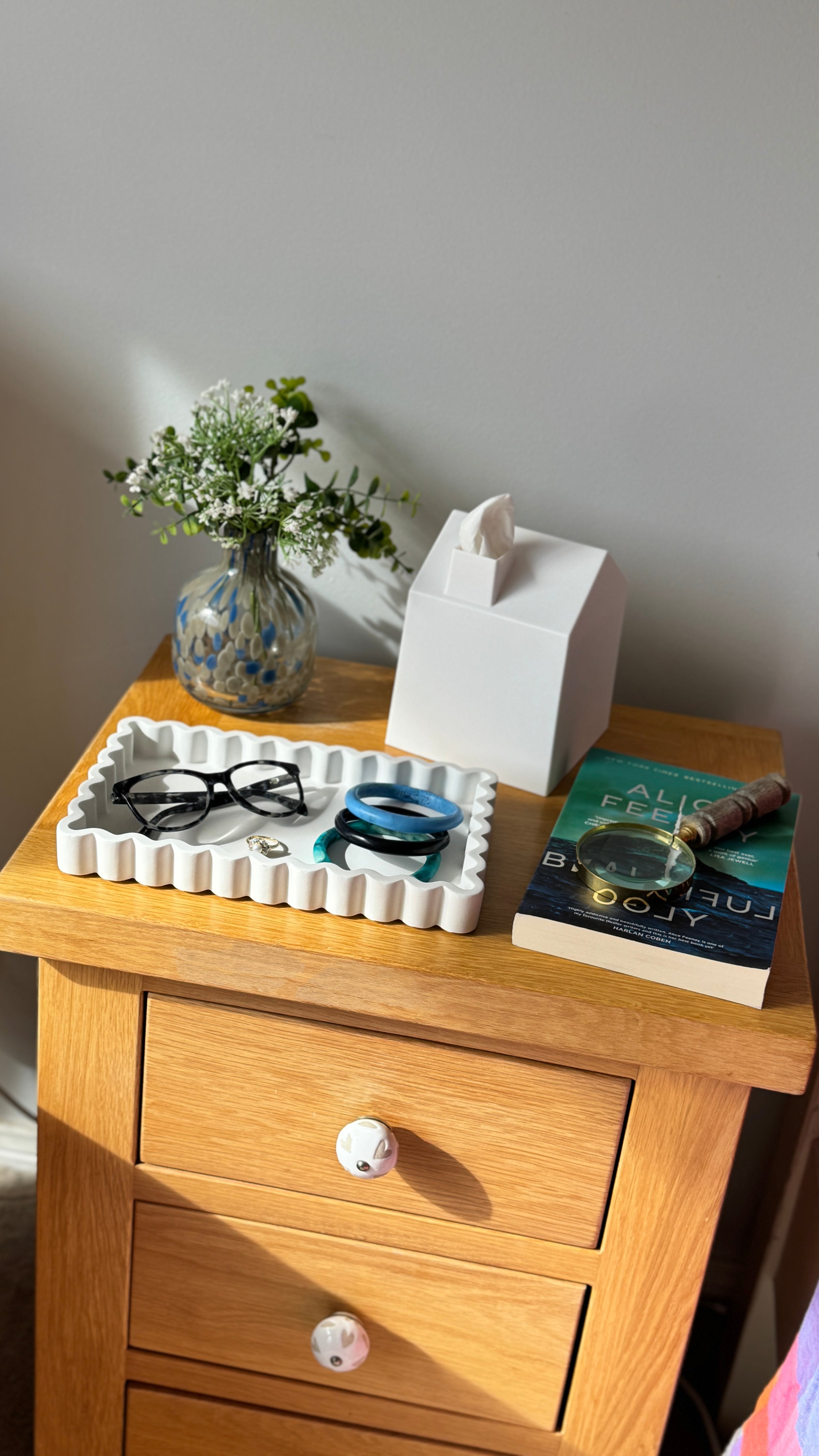 Wooden nightstand with a vase, glasses, and book on top