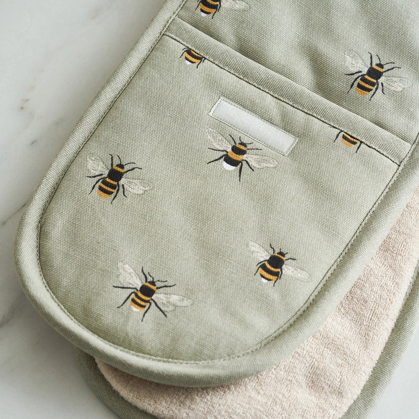 Green oven mitt with bee pattern on a marble surface