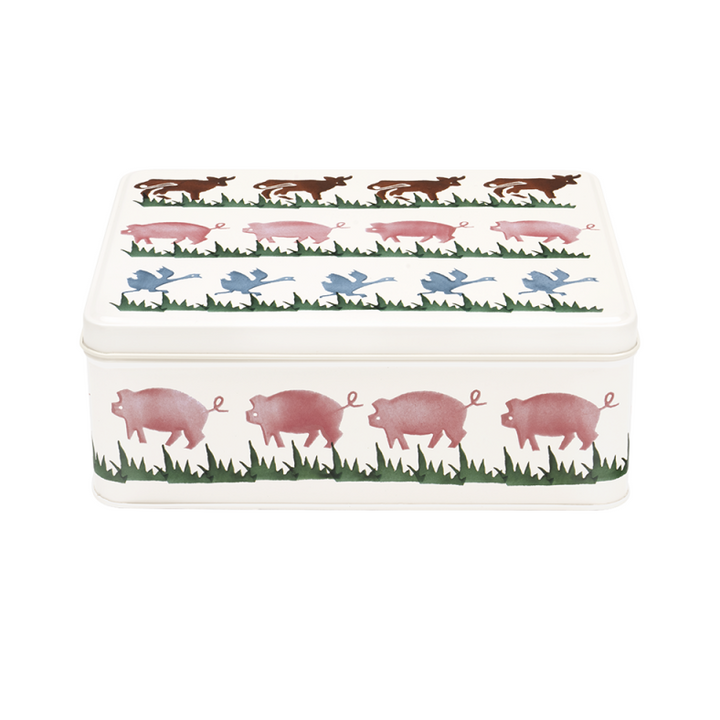 A rectangular metal storage tin with a lid, decorated with a repeating pattern of pink pigs in a grassy field and small blue birds, shown on a plain white background.