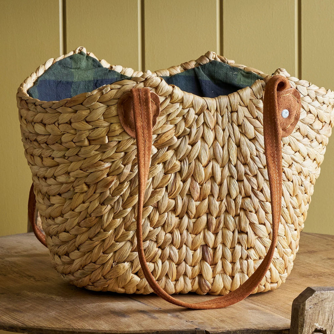 Woven straw bag with leather handles on a wooden surface