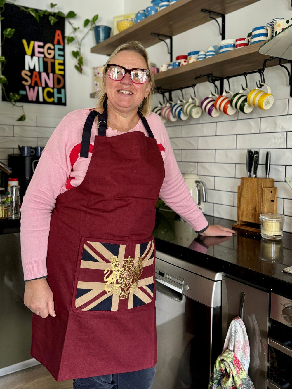 Person wearing a red apron with a Union Jack design in a kitchen.