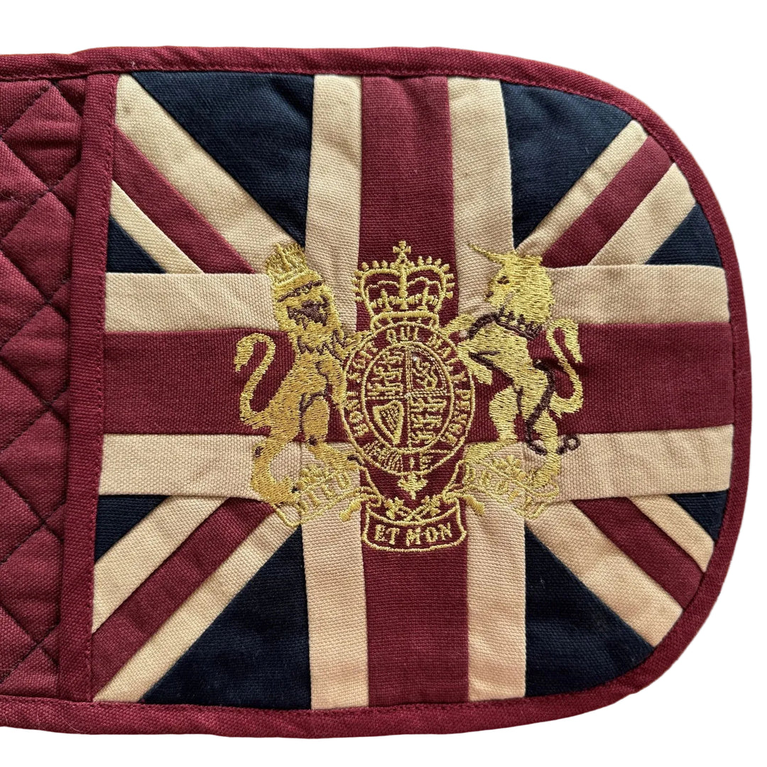 Oven mitt with Union Jack design and gold emblem on a wooden surface